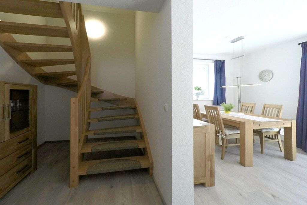 A wooden staircase leading to a dining area with a table and chairs.