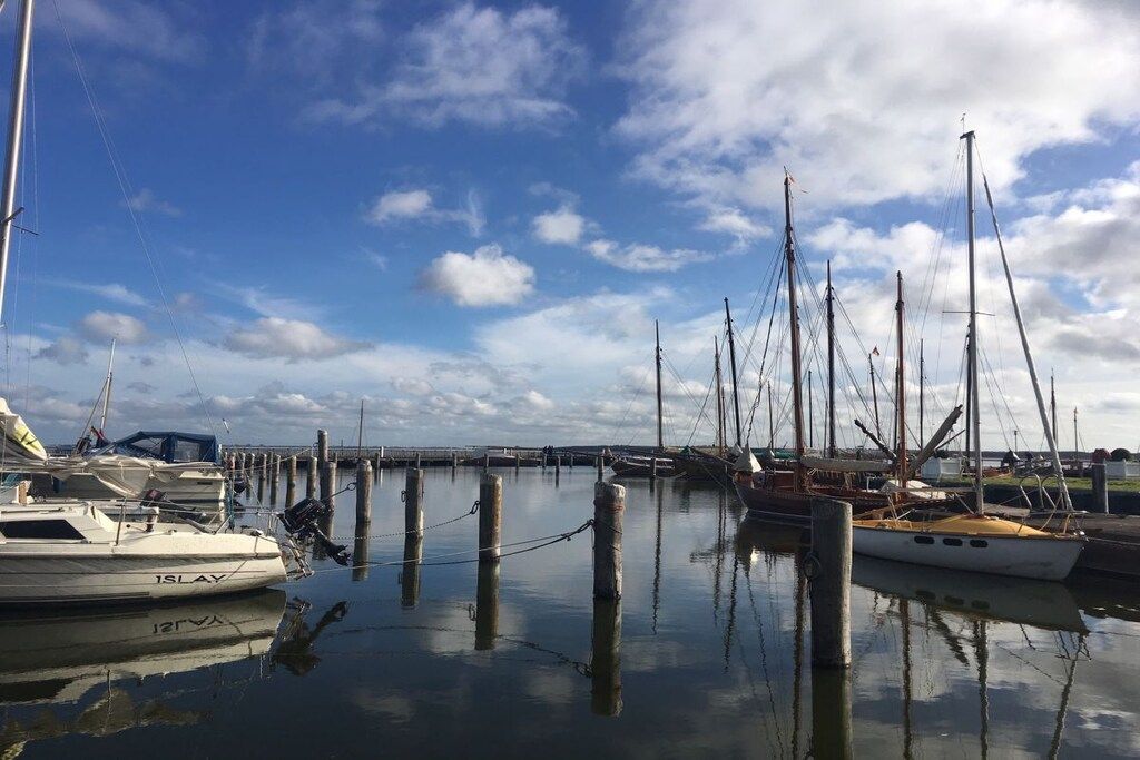 Een jachthaven met verschillende boten afgemeerd, rustig water en een heldere lucht.