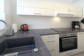 A modern kitchen with a sink, stove, and coffee maker. - Holiday home with 2 bedrooms (Dierhagen)