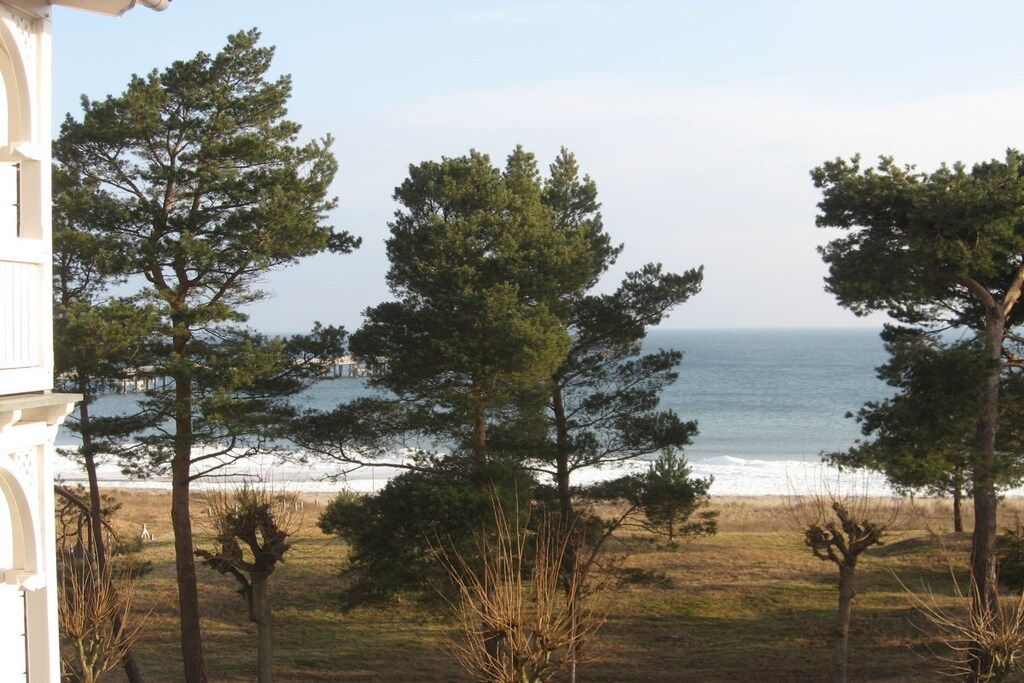 Eine Küstenlandschaft mit Blick auf das Meer, Bäume und ein Gebäude.