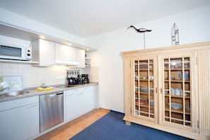 A kitchen with white cabinets, a dishwasher, a microwave, and a coffee maker. - Villa Freia Apt. 20 Granitz (Ostseebad Binz)