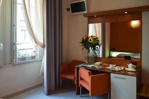 A hotel room with a dining area, a TV, a minibar, and a window with curtains. - Hotel Del Corso (Milan)
