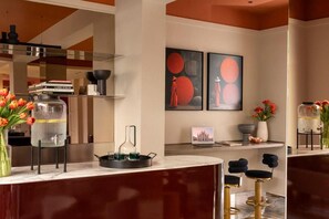 A modern kitchen with a marble countertop, a coffee machine, and a vase of tulips. - Hotel Del Corso (Milan)