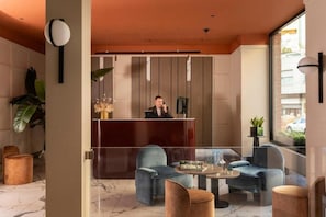 A hotel lobby with a reception desk, seating area, and large windows. - Hotel Del Corso (Milan)