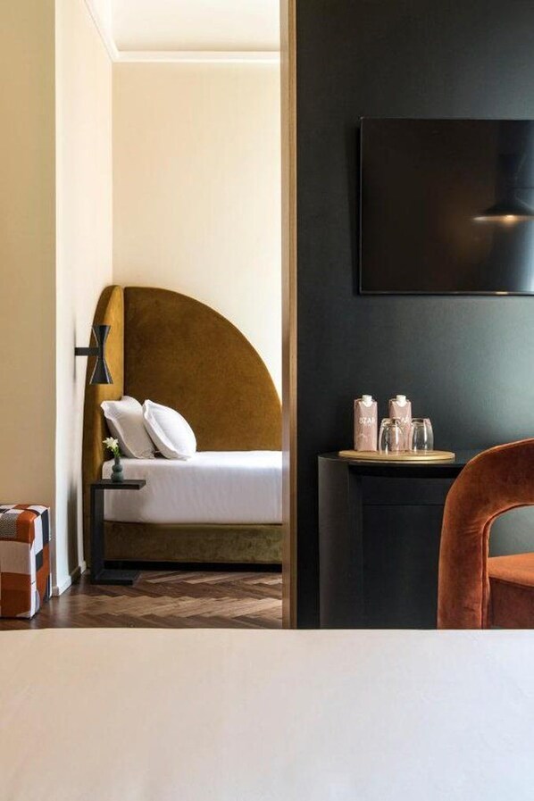 A hotel room with a bed, bedside table, and a TV mounted on the wall. - Hotel Del Corso (Milan)