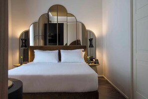 Ein Hotelzimmer mit einem großen Bett, einem hölzernen Kopfteil, zwei Nachttischlampen und einem Spiegel über dem Bett.
