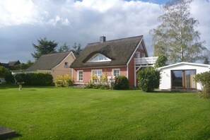 Ett rött hus med ett halmtak, ett vitt garage och en välskött gräsmatta.