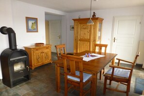 Ein Essbereich mit Holztisch und -stühlen, einem schwarzen Holzofen und einem Holzschrank.