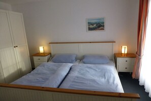 Ein Doppelbett mit zwei Nachttischen, einem Kopfteil, einem Kleiderschrank und einem Bild an der Wand.