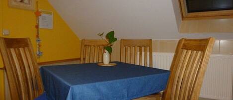 Un comedor con una mesa cubierta por un mantel azul, sillas de madera y una planta en maceta sobre la mesa.