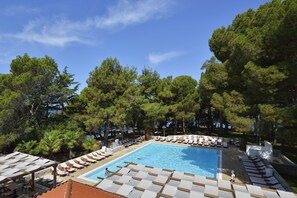 A swimming pool with lounge chairs and umbrellas, surrounded by trees. - Apartments Laguna Galijot (Porec)