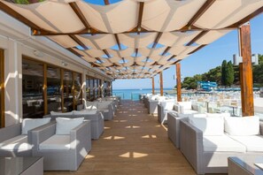 A covered outdoor seating area with wicker furniture and a view of the sea. - Apartments Laguna Galijot (Porec)