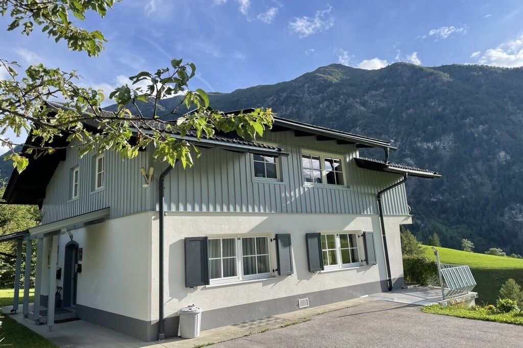 Un immeuble à deux étages doté d’un balcon, de grandes fenêtres et surplombant un paysage montagneux.