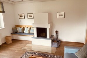 A living room with a fireplace, a sofa, a bench, and framed pictures on the wall. - Country House Glockner Dream (Heiligenblut am Großglockner)