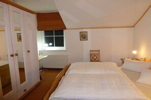 Une chambre à coucher avec un grand lit, une table de chevet avec une lampe, une fenêtre et une porte donnant sur une autre pièce.