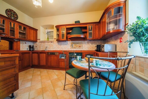 A kitchen with wooden cabinets, a round table with chairs, and a window with a plant.