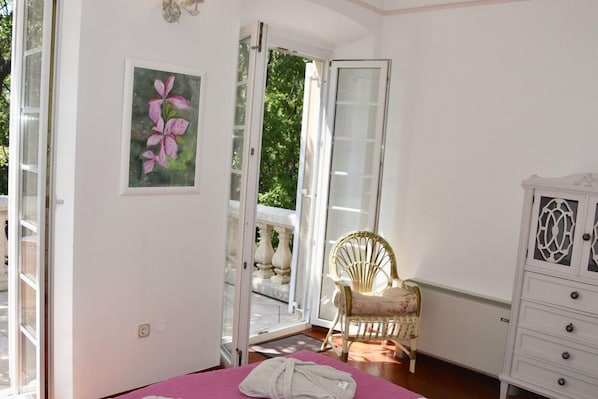Un dormitorio con una cama, una silla, un armario y una puerta que da a un balcón.