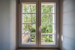 Una ventana con vistas a un jardín y árboles.
