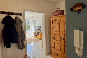 A hallway with coats hanging on a rack, a wooden cabinet, and a telephone on the wall. - Holiday apartment “Walter” on the Baltic Sea (Zingst)