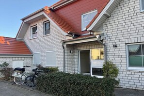 Ein zweistöckiges Gebäude mit rotem Dach, weißem Backstein-Fassade und einer Garagentür.