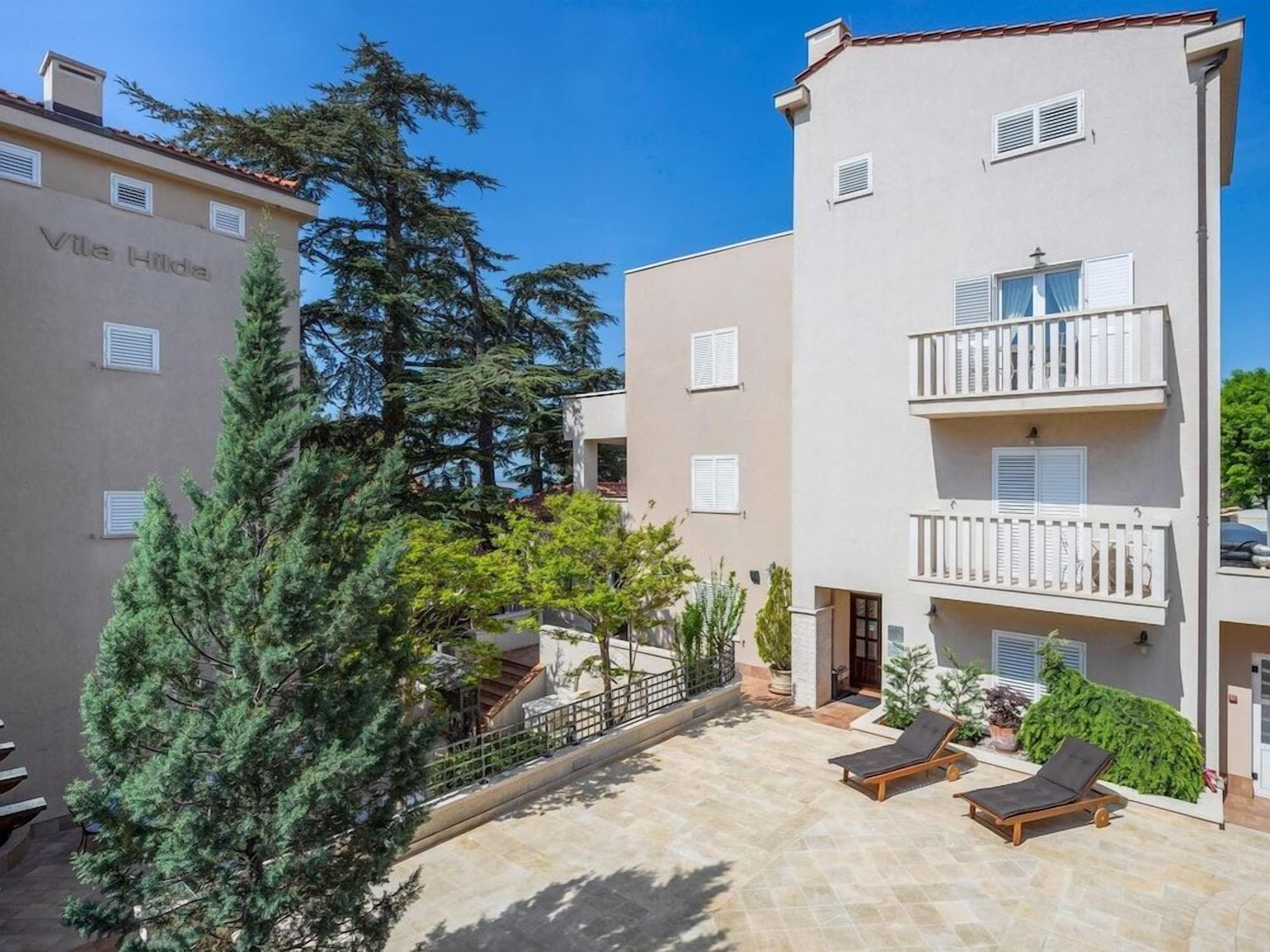 Un edificio residencial con balcones, un patio empedrado y un árbol.