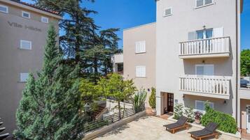 Un edificio residencial con balcones, un patio empedrado y un árbol.