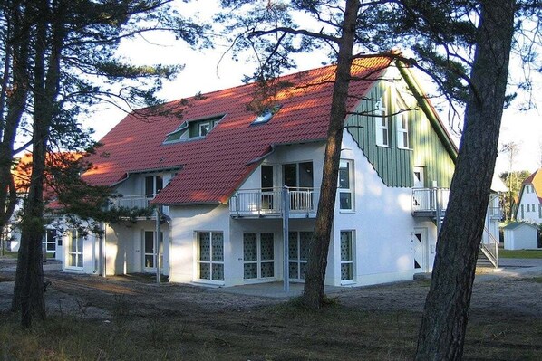 Punaisella katolla varustettu kaksikerroksinen rakennus, jossa on useita ikkunoita ja parveke.