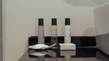 A bathroom counter with toiletries including a bottle of body lotion and a bottle of body spray.