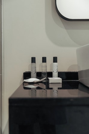 Tocador de baño con artículos de aseo, incluyendo una botella de loción corporal y un atomizador de perfume.