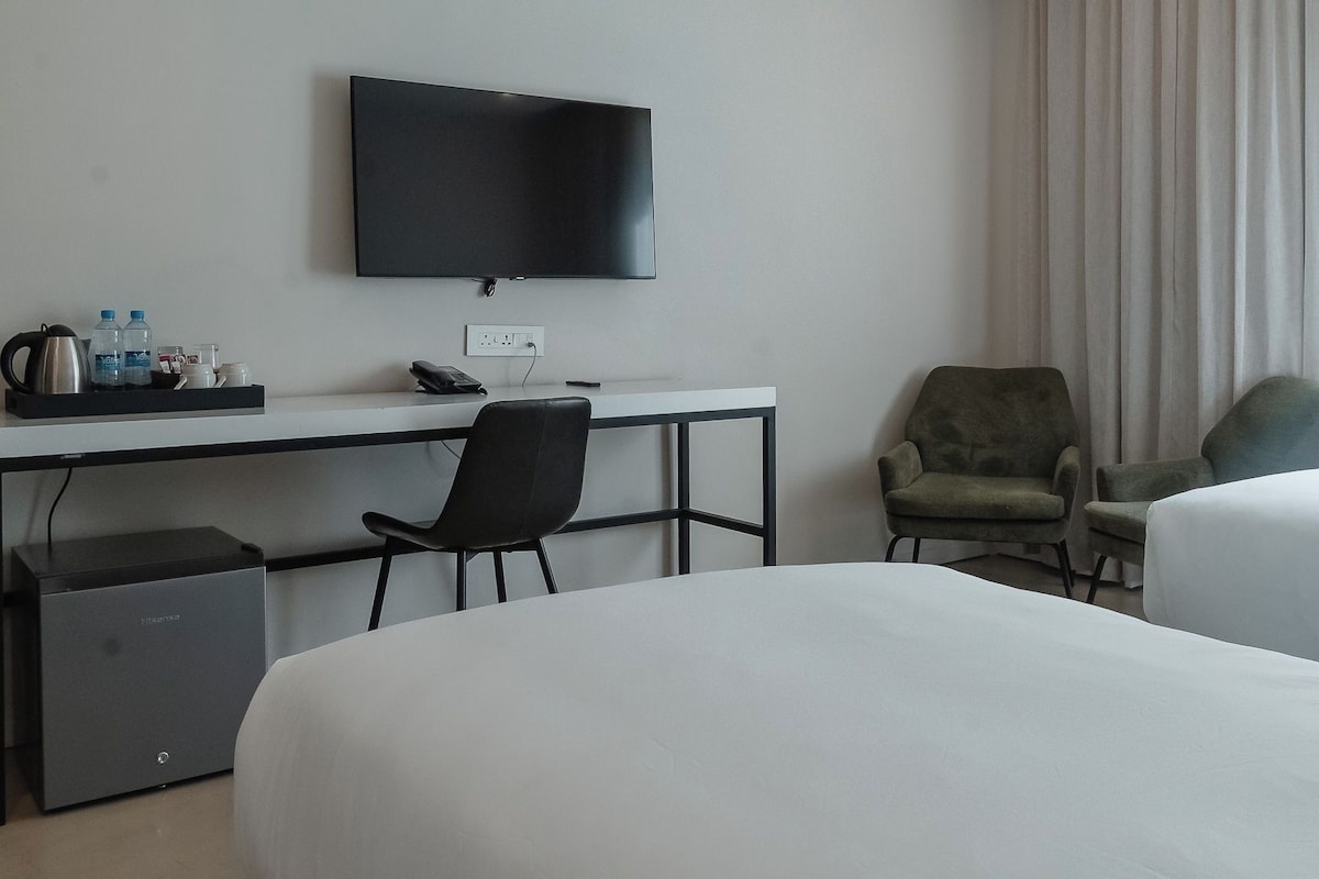 Habitació d'hotel amb llit, escriptori amb televisió, cadira i un petit armari.