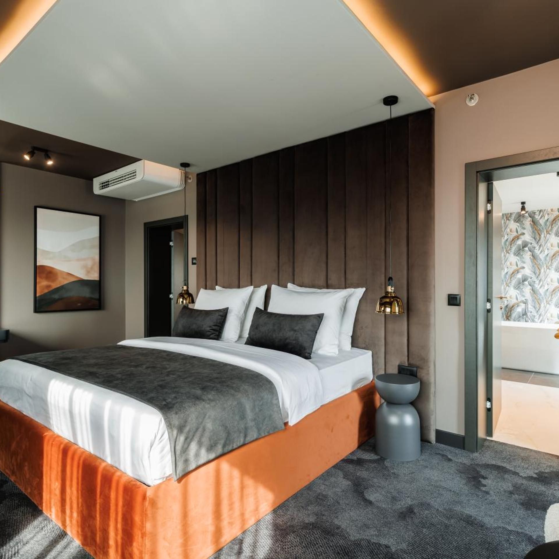 Ein modernes Schlafzimmer mit einem großen Bett, einer Wand-Klimaanlage und einer Tür zu einem Balkon.