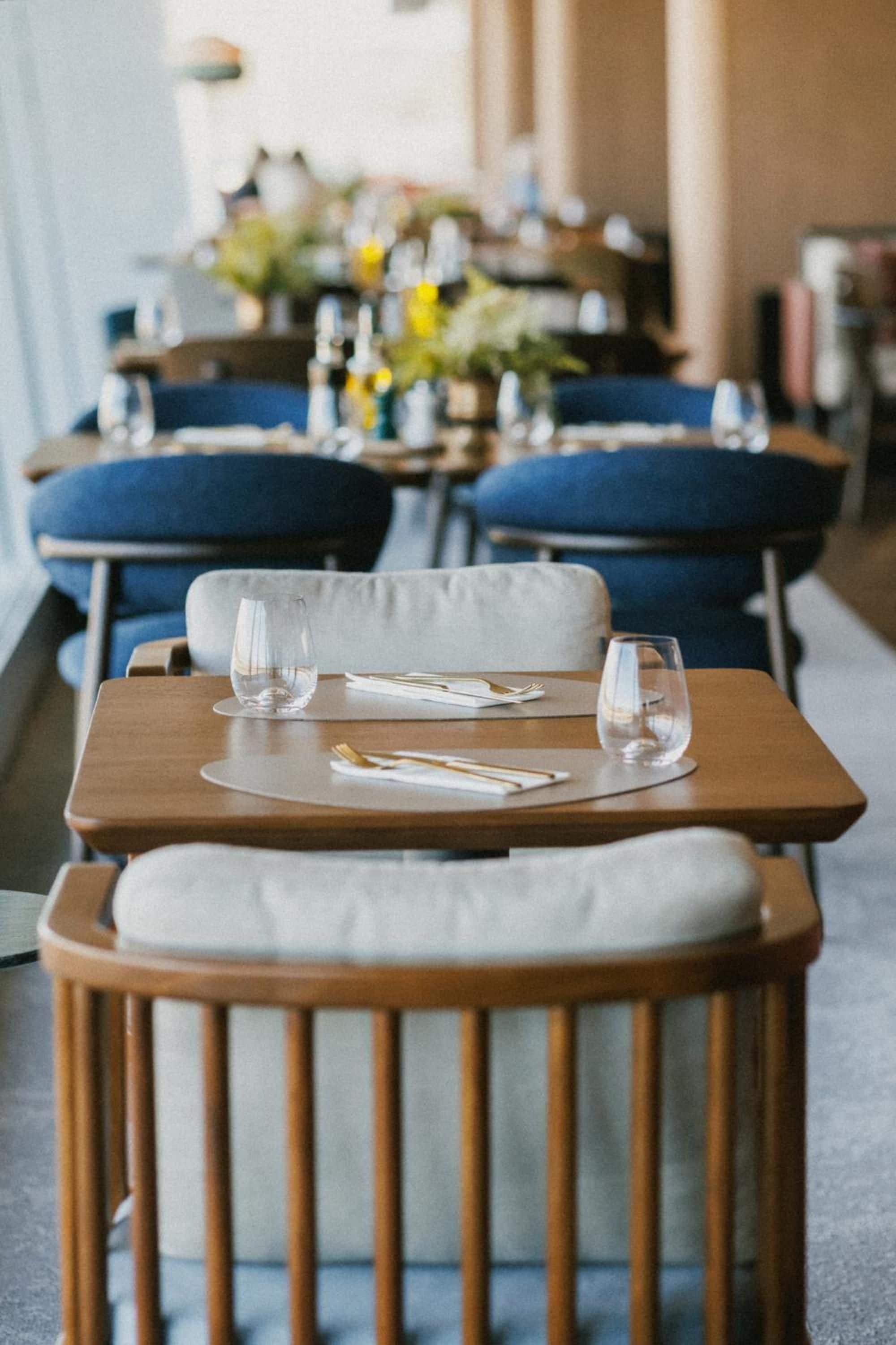 Ein Restaurant mit gedeckten Tischen, bequemen Sitzgelegenheiten und sauberem Glasgeschirr.