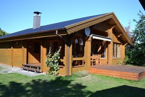A wooden cabin with a porch, a chimney, and a deck. - Holiday home with 2 bedrooms (Ahrenshoop)