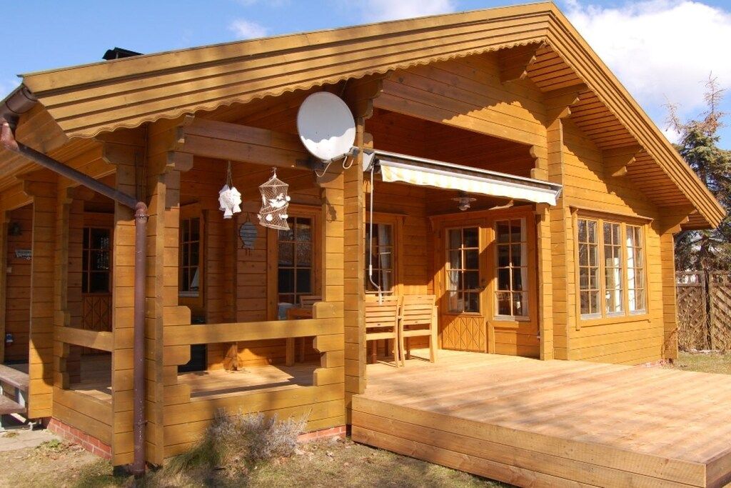 Une cabane en bois avec une véranda, une antenne parabolique et une nichoir.