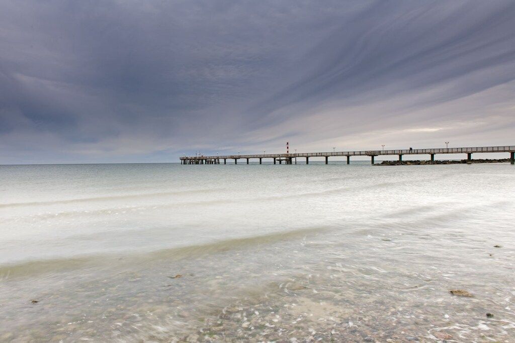 A pier extending into calm waters with clear skies above.