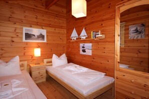 Een houten kamer met een bed, nachtkastjes, een wandplank met boeken en decoratieve objecten, en een lijst met een afbeelding.