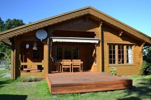Een houten chalet met een veranda, een schotelantenne en een overdekt zitgedeelte.