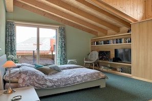 Une chambre à coucher comprenant un lit, un bureau, une chaise, une bibliothèque et un téléviseur.
