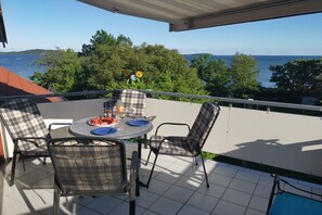 Ein Balkon mit Tisch und Stühlen mit Blick auf Wasser und Grünflächen.