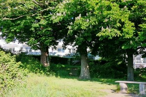 Een park met bomen, een bankje en een gebouw op de achtergrond.