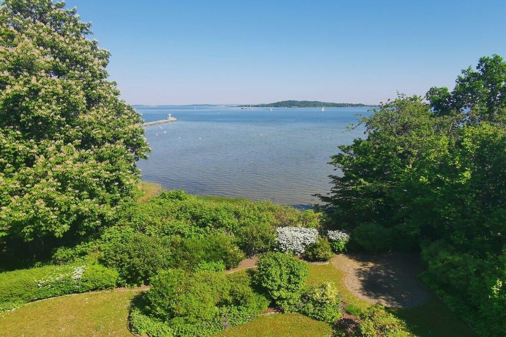 Vista de un lago con barcos, rodeado de abundante vegetación y árboles.