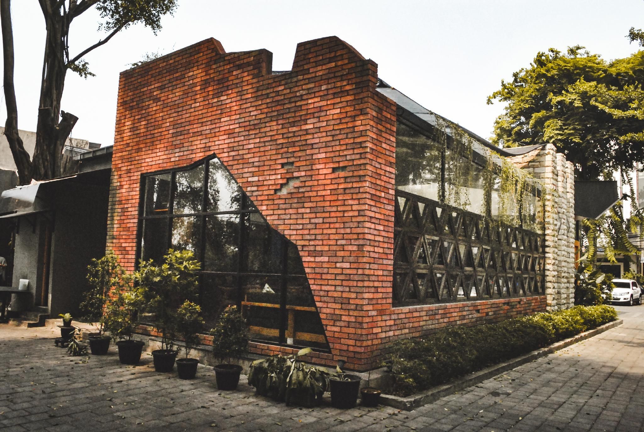 A modern building with a brick facade, large windows, and potted plants.