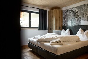 A bedroom with a bed, a window, a wall-mounted artwork, and wooden cabinetry. - 5803 Alm-Lodge trais (Gargellen)