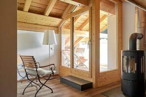Ein Holzinnenraum mit Kamin, einer Bank und Blick durch eine Glastür.