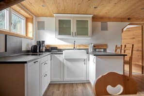 A compact kitchen with white cabinets, a black countertop, and a wooden ceiling. - 5405 Elfriede in the Alpenhaus Montafon (Bludenz)