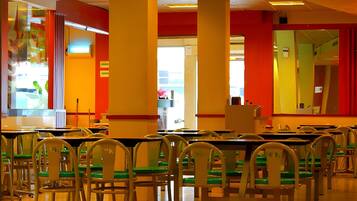 A cafeteria with rows of tables and chairs, a bright interior, and a view of the outside.