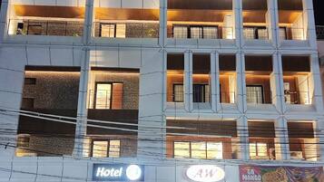 A multi-story hotel with balconies, a restaurant, and a visible sign for a mango dessert.