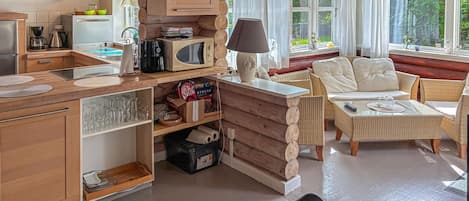 Una cocina acogedora con armarios de madera y un comedor con mobiliario de mimbre.