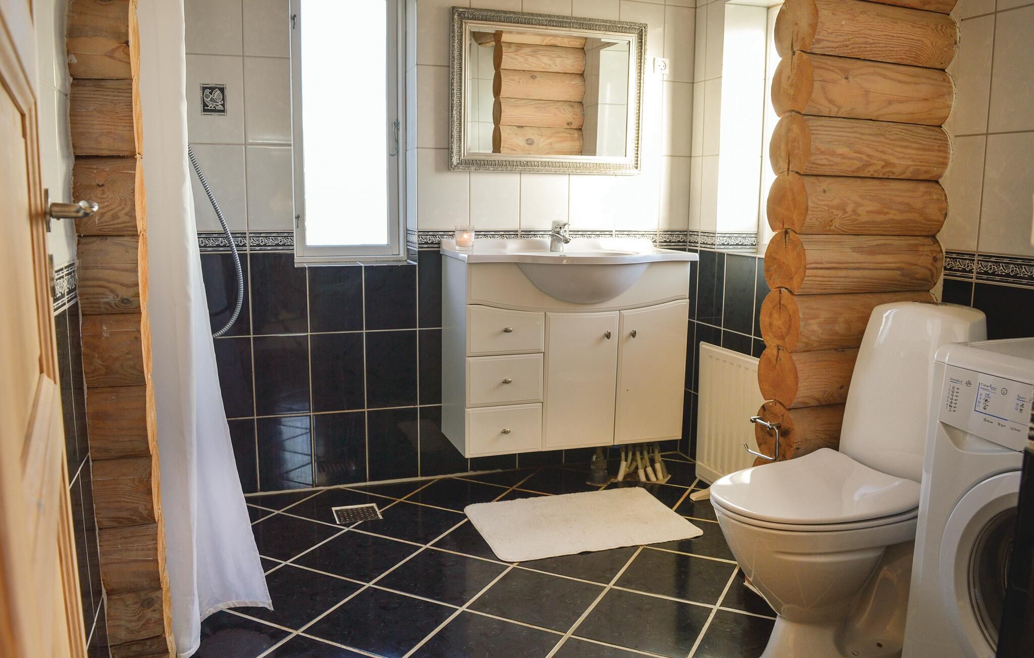 Une salle de bain avec un sol carrelé en noir et blanc, un lavabo blanc, un miroir et des toilettes.