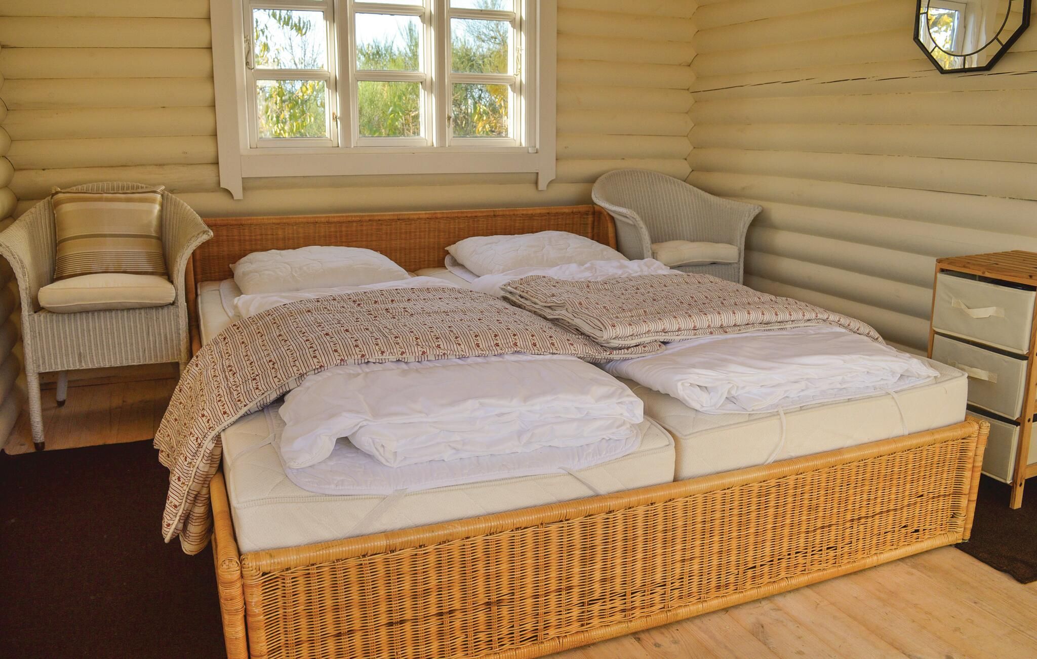 A room with a bed, a chair, a nightstand, and a window.
